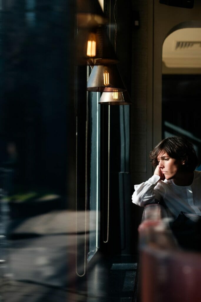 A woman with short brown hair looking out a window.