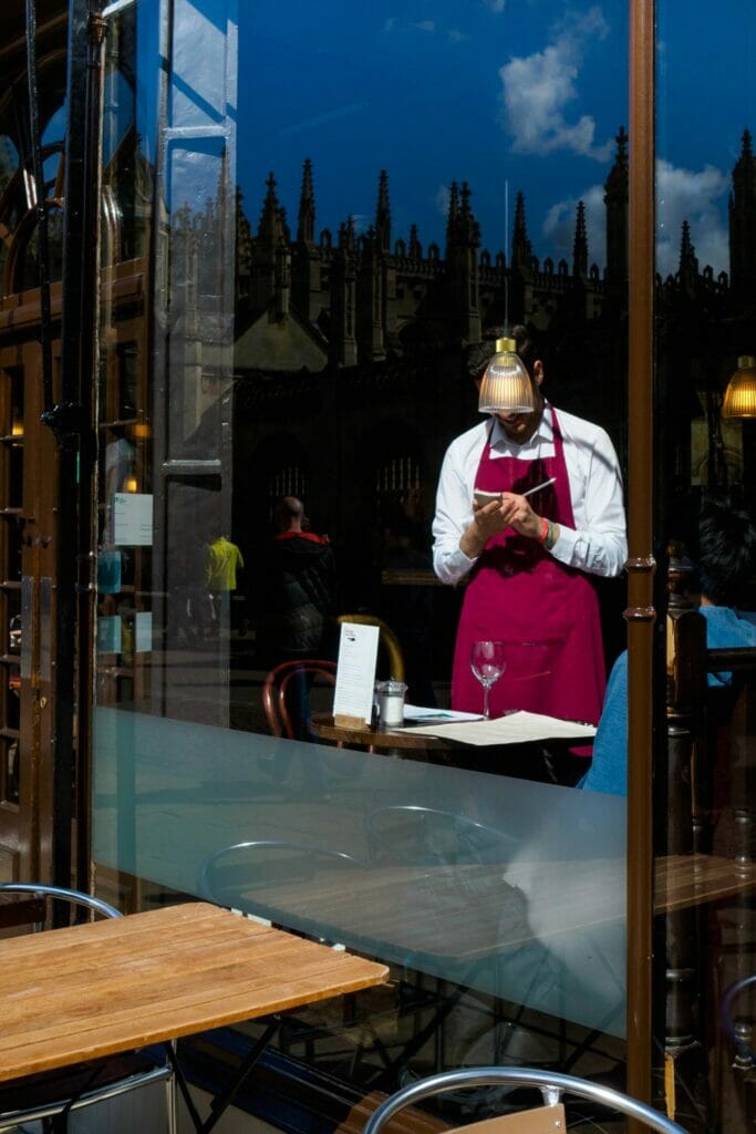 A waiter in a red apron taking an order.