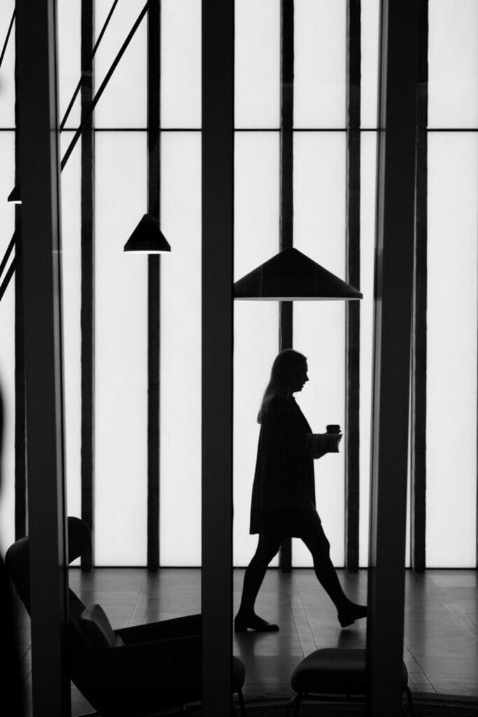 A woman's silhouette under a lamp and in front of vertical beams.