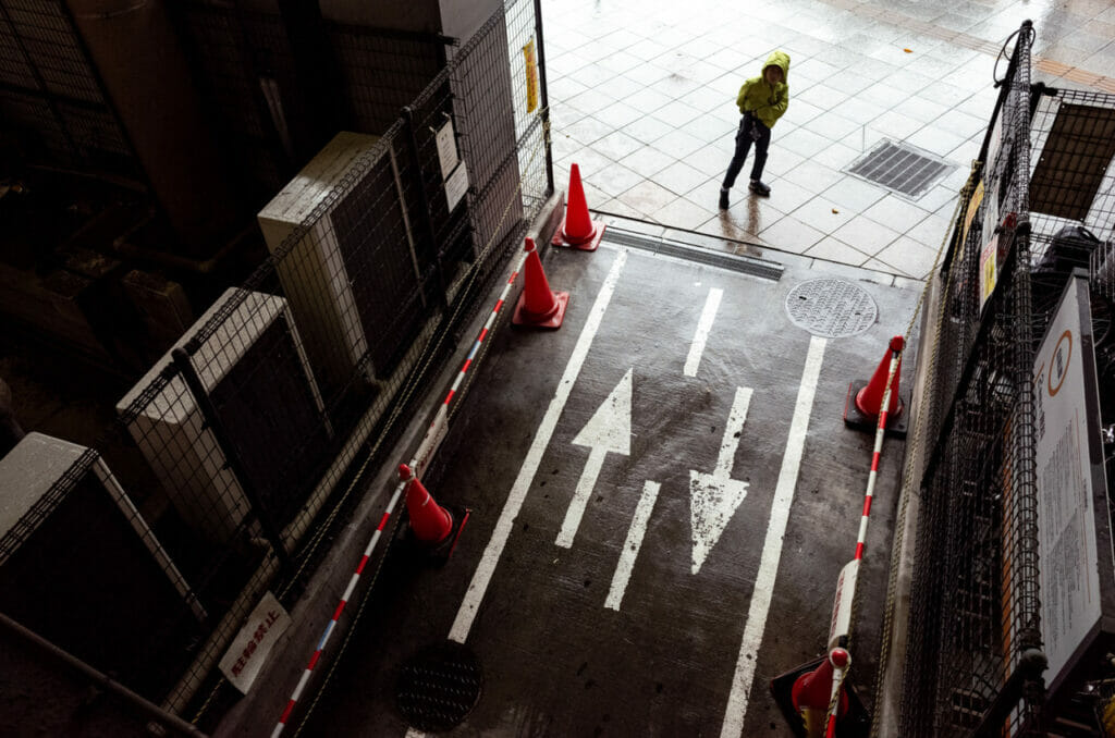 A man looking up in a yellow rain coat in the rain.